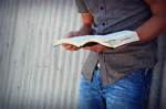 man standing reading Bible
